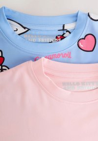 Magliette di cotone blu e rosa impilate, con un design a cuore sulla maglietta blu e una texture liscia sulla maglietta rosa.