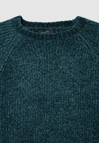 Türkiser Strickpullover mit einem strukturierten Muster, geripptem Ausschnitt und Raglanärmeln. Der Stoff wirkt weich und dehnbar, mit dem Etikett "CALLIOPE."