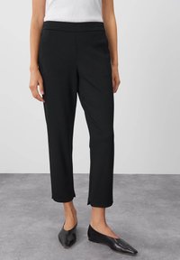 Svart kortbyxor gjorda av stretchigt tyg, med en mjuk midjeband och rak bendesign. Matchat med svarta ballerinas.