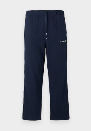 Pantalon de jogging bleu marine Calvin Klein avec taille élastique, cordon et logo blanc sur la partie supérieure de la cuisse gauche.