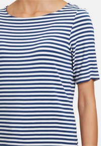 Kortärmad topp i bomull med kontrasterande blå och vita horisontella ränder, rundad halsringning och en mjuk, lätt textur.