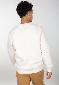 Lysbeige sweatshirt lavet af en bomuldsblanding, med rund hals og ribbede manchetter. Glat tekstur med et enkelt design, ingen synlige mønstre.