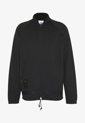 Czarna kurtka zapinana na zamek, wykonana z miękkiego materiału. Posiada rękawy raglanowe, wysoki kołnierz oraz ściągacz na dole. Zawiera logo marki oraz szczegóły metki.