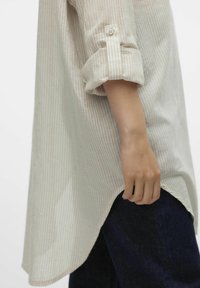 Camicione lungo a righe leggere in cotone crema e beige, con orlo arrotondato, maniche arrotolate e chiusura a bottoni sui polsini.