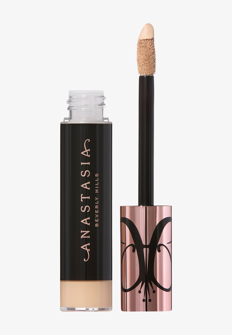 Correcteur liquide dans un flacon en verre transparent avec un bouchon noir. Dispose d'une embout applicateur souple. Le design comprend un accent en or rose avec un logo élégant.