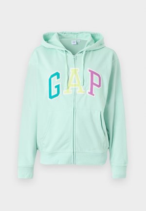 Mintgrøn zip-up hoodie med store, multikolorede "GAP" bogstaver. Inkluderer hætte med snoretræk og frontlommer. Blød stoftekstur.