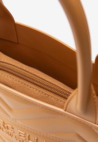 Borsa a tracolla color tan con una texture trapuntata, dotata di una tasca interna con zip in tessuto e manici lisci, che mette in evidenza il suo design funzionale.