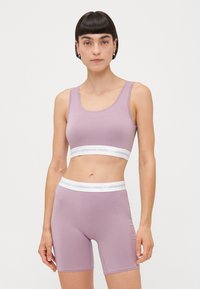 Lilac seamless sports bra and matching shorts, both with white elastic bands. The fabric appears soft with a smooth texture.