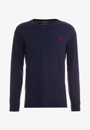 Tengerési kék, hosszú ujjú pamut póló, kerek nyakkivágással. Bal mellen található egy kicsi, piros polo logó. Puha tapintású.