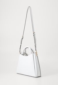 Borsa a mano bianca con finitura testurizzata, manici doppi, una tracolla regolabile e dettagli in hardware dorato. Presenta un design angolare unico.
