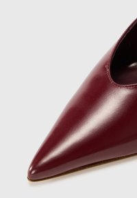 Bordeaux leren puntige schoen met uitsnijdetails. Gladde textuur en slank ontwerp, met een lage profiel en minimale hardware.
