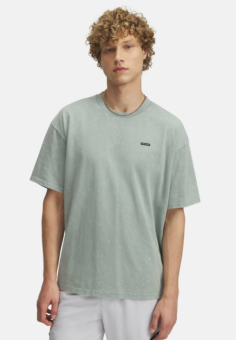 Mintgrøn oversized t-shirt lavet af blødt bomuldsstof, med korte ærmer og et lille logo-patch på brystområdet. Glat tekstur.