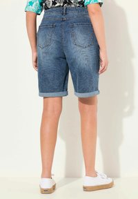 Denim bermudan shortsit, joissa on käännetyt lahkeet, vaaleansininen pesu ja kaksi takataskua. Yhdistetty valkoisiin espadrille-kengiin.