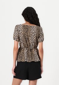 Top a maniche corte con stampa leopardata in tonalità di marrone e nero, con vita a peplum. Tessuto morbido e scollatura rotonda, abbinato a pantaloni corte neri.