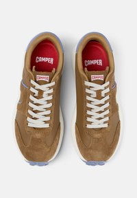 Brown sneakers made of leather and suede, featuring white laces, a red insole, and light purple accents on the upper.