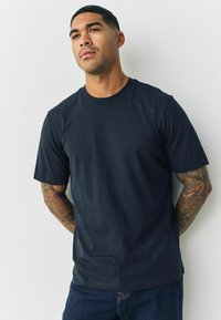 Tumši jūras zila īsām piedurknēm kokvilnas t-krekls ar apaļu dekoltē, gluda tekstūra, parasts piegriezums un smalki šuvumi. Saskaņots ar džinsiem.