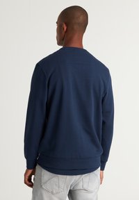 Felpa girocollo di colore blu navy realizzata in tessuto texturizzato, con polsini e orlo a coste, dal design semplice e senza grafiche visibili.