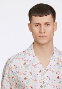 Camisa de manga corta con botones, que presenta una base blanca y un colorido patrón submarino, incluyendo peces, coral y plantas acuáticas.
