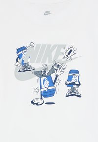 Tris mėlynų Nike dėžių su rankomis ir kojomis, apsirengusių sportiniais batais, atliekančių breakdance judesius virš didelio pilko Nike logotipo.