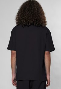 Schwarzes T-Shirt mit kurzen Ärmeln und einem lässigen Schnitt. Weicher Stoff, gerader Saum und keine sichtbaren Etiketten oder Logos. Einfaches Design mit einem cleanen Rücken.