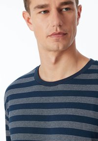 Chemise à rayures bleu marine à manches longues avec de fines rayures horizontales blanches, dotée d'un col rond et d'une texture en coton doux.