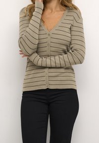 Beige randig kardiagan med knappstängning, ribbad textur, V-ringning och långa ärmar. Matchad med mörka jeans.