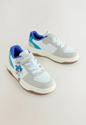 White and gray sneakers with blue accents, suede and synthetic materials, perforated toe, and a Sonic character graphic on the side.