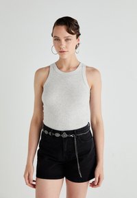 Un maieu gri cu dungi, asortat cu pantaloni scurți negri cu talie înaltă, având un curea metalică și cercei cerc. O ținută simplă și casual.