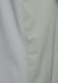 Lichtgrijze stof met aan de linkerkant een gladde sectie en aan de rechterkant een gestructureerde sectie met een rasterpatroon.