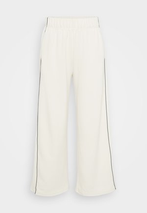 Pantalons de survêtement larges en crème avec une texture douce, dotés de bandes latérales noires et d'une taille élastique pour plus de confort et de facilité d'utilisation.