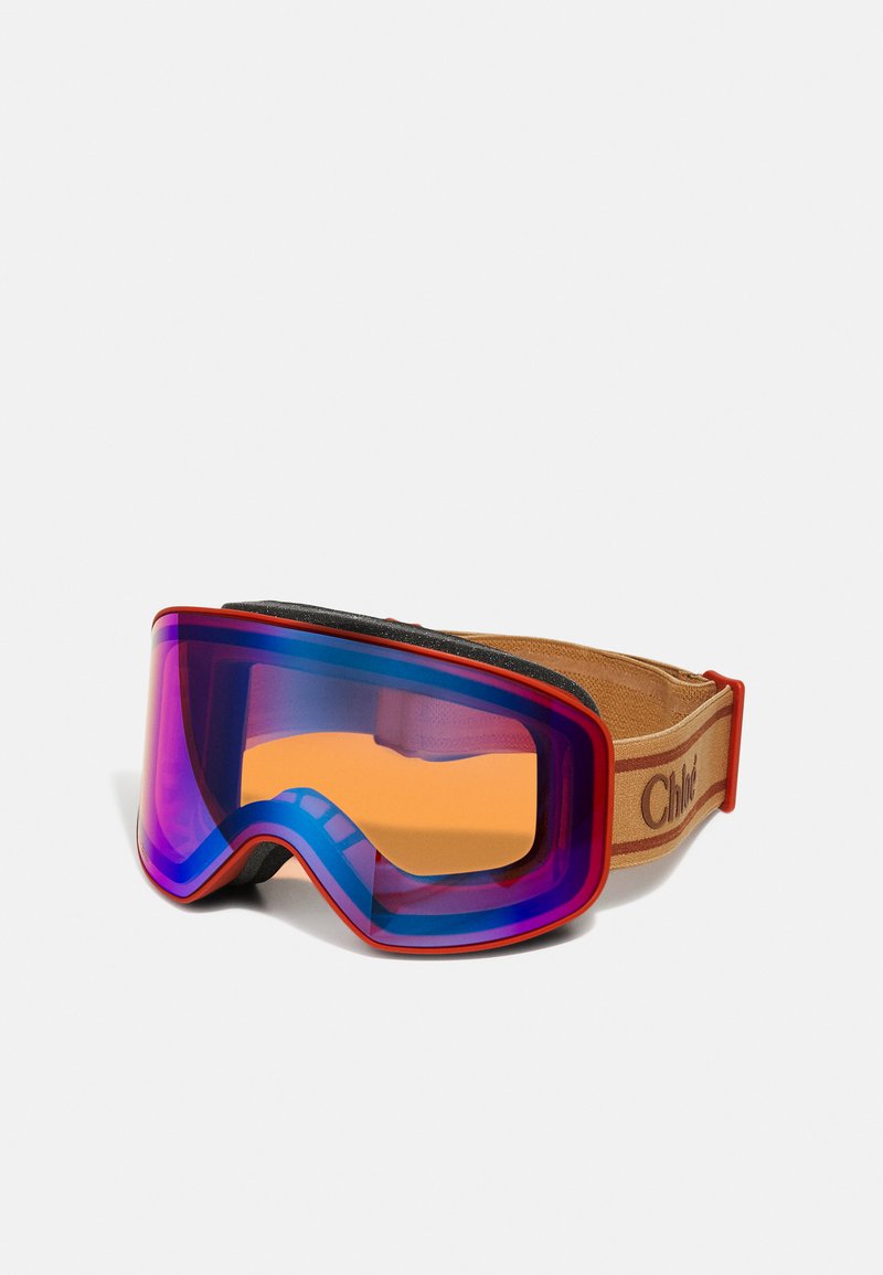 Skibrille mit einer gebogenen lila und orangefarbenen Linse, rotem und beigefarbenem Riemen sowie einer strukturierten schwarzen Schaumstoffpolsterung für Komfort und Sitz.