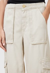 Beige cargobroek gemaakt van een katoenmix, met dubbele frontzakken, een knoopsluiting en gestikte details langs de naden.