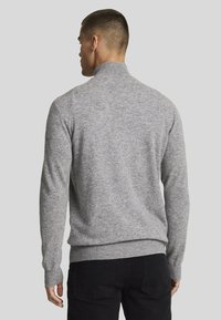Maglione grigio con collo alto, maniche lunghe e polsini a coste. Texture morbida con un aspetto liscio, design aderente.
