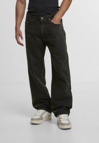 Mustat denim leveälahkeiset farkut haalistuneella pinnalla, joissa on viisi taskua, nappikiinnitys ja merkkipatch takavöärillä.