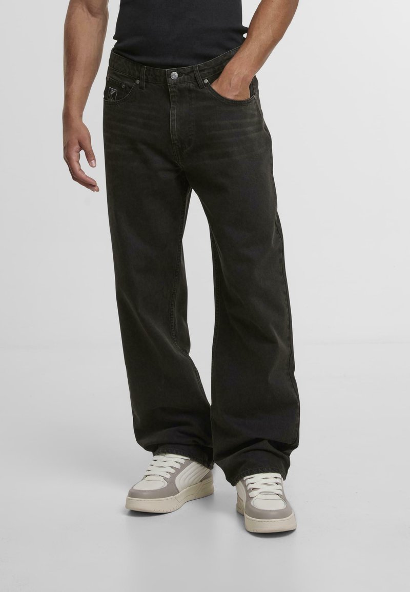 Mustat denim leveälahkeiset farkut haalistuneella pinnalla, joissa on viisi taskua, nappikiinnitys ja merkkipatch takavöärillä.