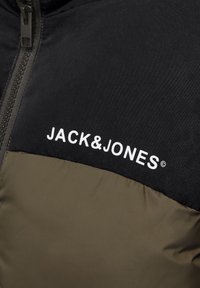 Doudoune avec une section supérieure noire et une section inférieure verte olive, ornée d'un logo blanc "JACK&JONES" sur la poitrine. Texture lisse.