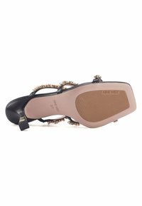 Sandal nero con tacco alto, decorato con perline, con cinturini sottili e una soletta solida e testurizzata che presenta un piccolo tacco a blocco.
