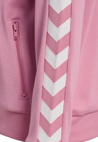 Rucksack aus pinkem Stoff mit seitlicher Reißverschlusstasche und weißem Chevron-Muster entlang des Riemens. Glatte Textur und robustes Design.