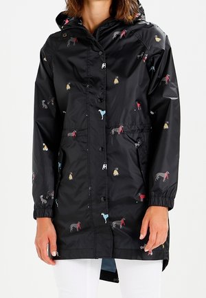Black hooded raincoat with multicolored small dog patterns, front buttons, elastic cuffs, and side pockets worn by a person.