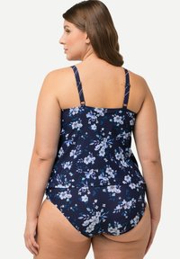 Tankini à imprimé floral bleu marine avec des bretelles réglables, mettant en avant des fleurs bleu clair et blanches. Tissu lisse avec une coupe ajustée.