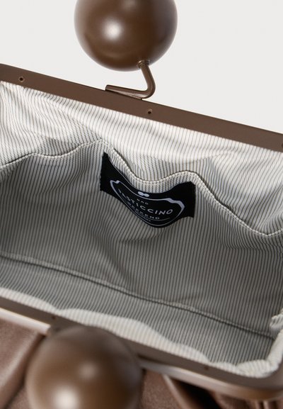 Intérieur de pochette marron avec doublure rayée, armature métallique et deux fermoirs sphériques. Comprend une étiquette de marque sur un côté.