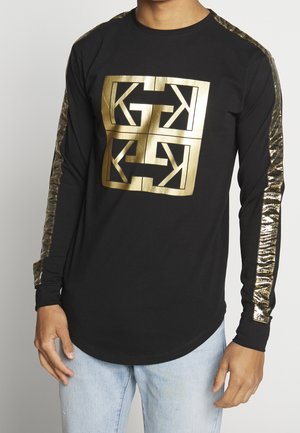 Long-sleeve black shirt with a large gold graphic design on the front, featuring shiny metallic accents along the sleeves.