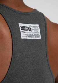 Anglies pilkos spalvos maišelis, pagamintas iš 88 % ekologiškos medvilnės ir 12 % poliesterio, su ryškiu baltu etiketu su juodu tekstu ir grafika.