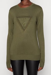 Maglione verde oliva con maniche lunghe, scollatura a girocollo, caratterizzato da un logo triangolare in rilievo tono su tono con borchie al centro, polsini e orlo a coste.