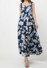 Maxi sukienka w granatowym materiale z białymi nadrukami orchidei. Posiada kwadratowy dekolt, szerokie ramiączka oraz zwiewny krój z zakładkami.