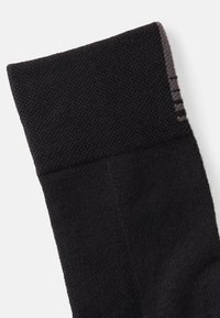 Meia preta com punho texturizado e canelado. O corpo principal apresenta um padrão de malha suave. Listras horizontais sutis em cinza no punho.