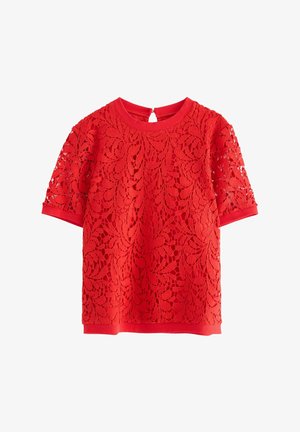 Rød kortærmet bluse med floralt blondeoverlæg, rund halsudskæring og en lille knaplukning bagpå.