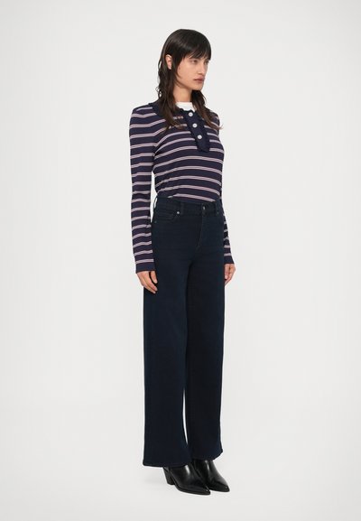 Triibuline tumelilla pikkade varrukatega top heledate roosade triipude ja nööpidega; kombineeritud kõrge vöökohaga tume teksariidest laiade säärtega pükstega ja mustade saapadega.