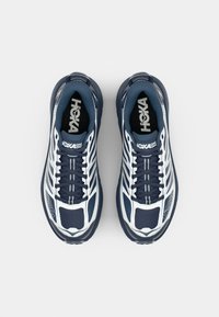 Námořnické běžecké boty s bílými akcenty, síťovaná svrchní část, polstrovaná podrážka a silná gumová podrážka. Obsahují tkaničky a logo na jazyku.