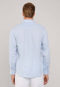 Camicia azzurro chiaro a maniche lunghe realizzata in tessuto lavorato. Presenta un delicato motivo a quadretti, polsini con bottone e una piega centrale sul retro per facilitarne i movimenti.